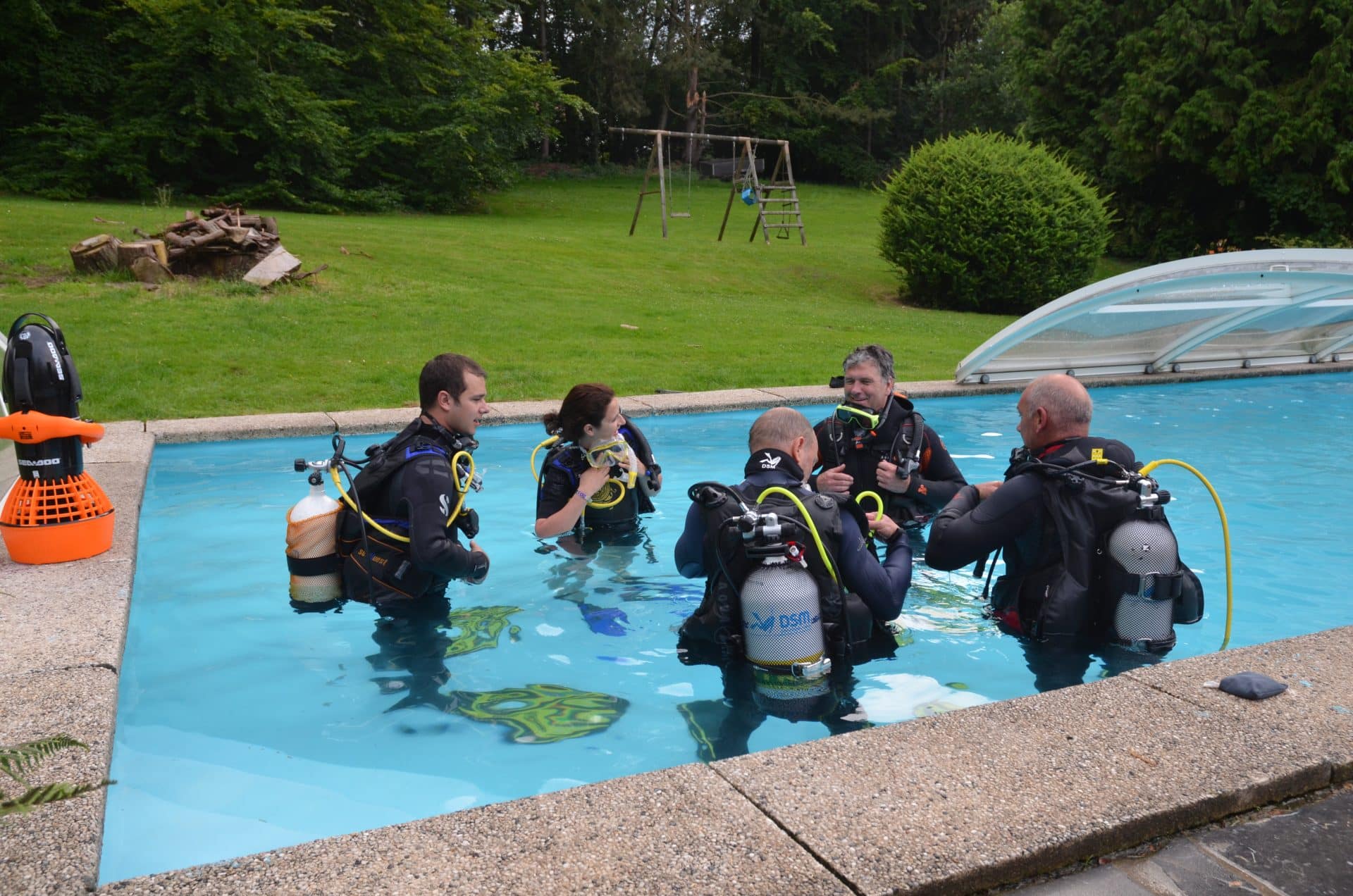 Groupe de plongeur en combinaison dans une piscine pour apprendre la plongée